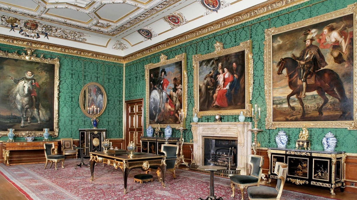 Windsor Castle interior with ornate paintings and antique furniture in a richly decorated room.