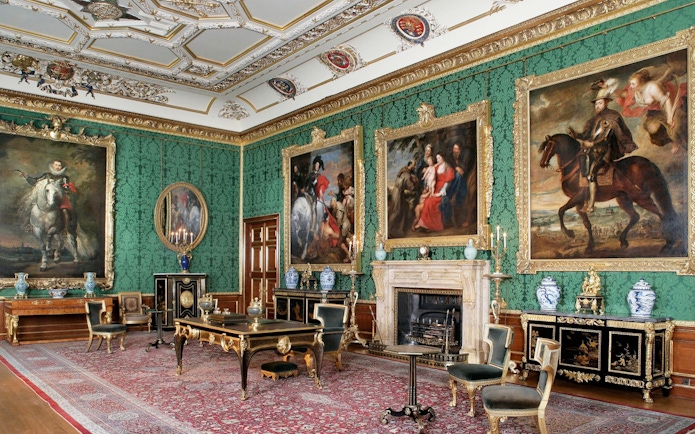 Windsor Castle interior with ornate paintings and antique furniture in a richly decorated room.