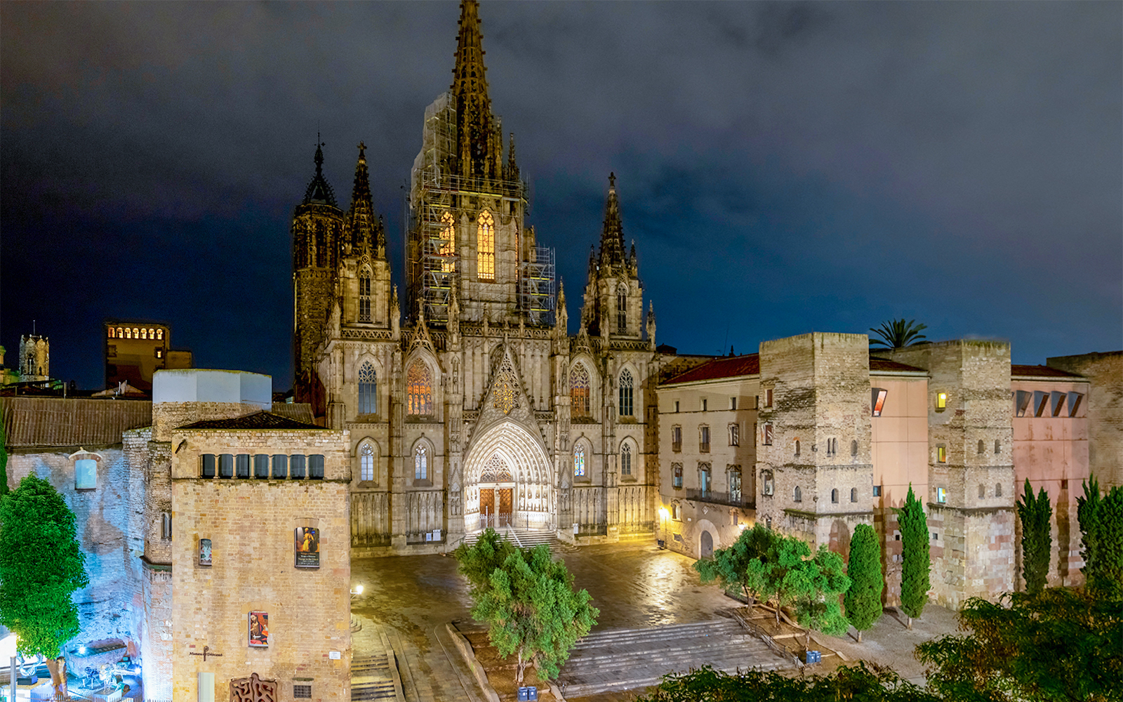 Barcelona Cathedral illuminated at night in El Born district square.