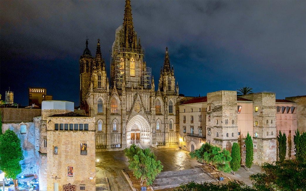 Barcelona Cathedral illuminated at night in El Born district square.