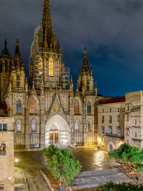 Barcelona Cathedral illuminated at night in El Born district square.