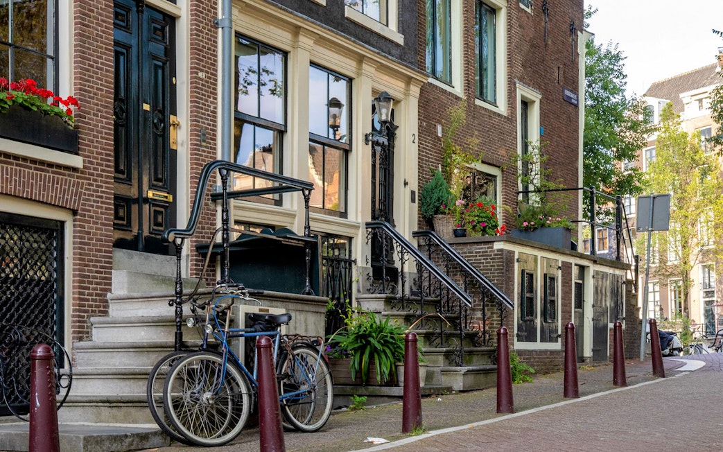 Historic Amsterdam canal houses with bicycles and flower boxes.