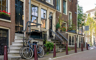 Historic Amsterdam canal houses with bicycles and flower boxes.