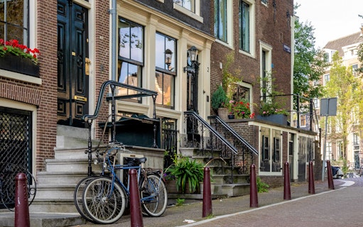 Historic Amsterdam canal houses with bicycles and flower boxes.
