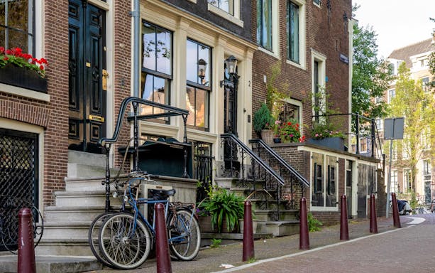 Historic Amsterdam canal houses with bicycles and flower boxes.