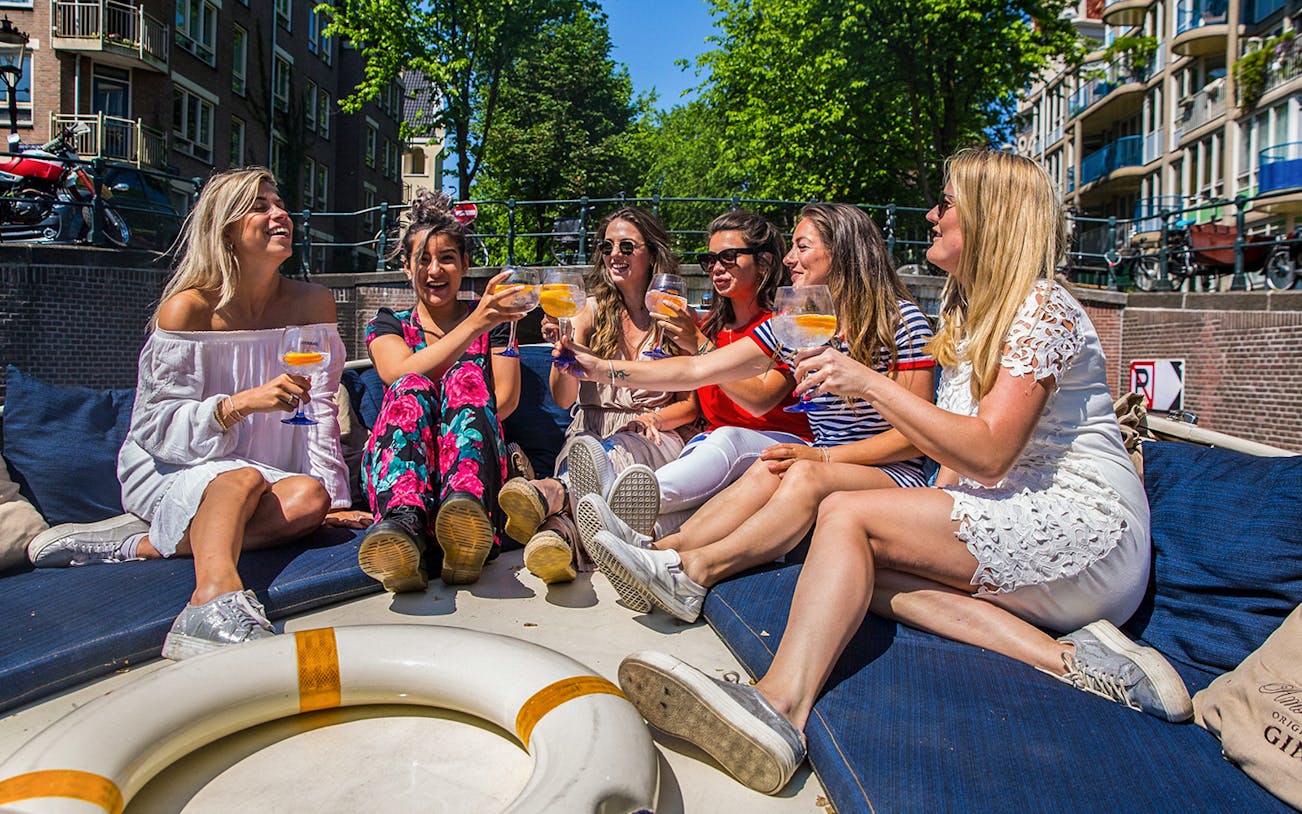 Group enjoying drinks on a canal cruise in Amsterdam.