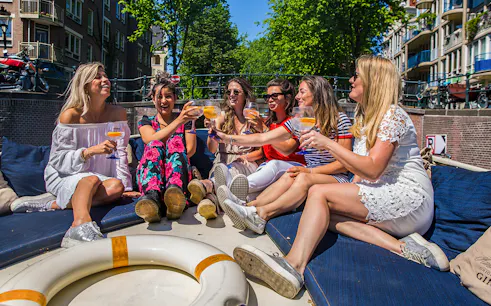 Group enjoying drinks on a canal cruise in Amsterdam.