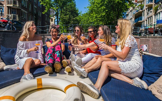 Group enjoying drinks on a canal cruise in Amsterdam.
