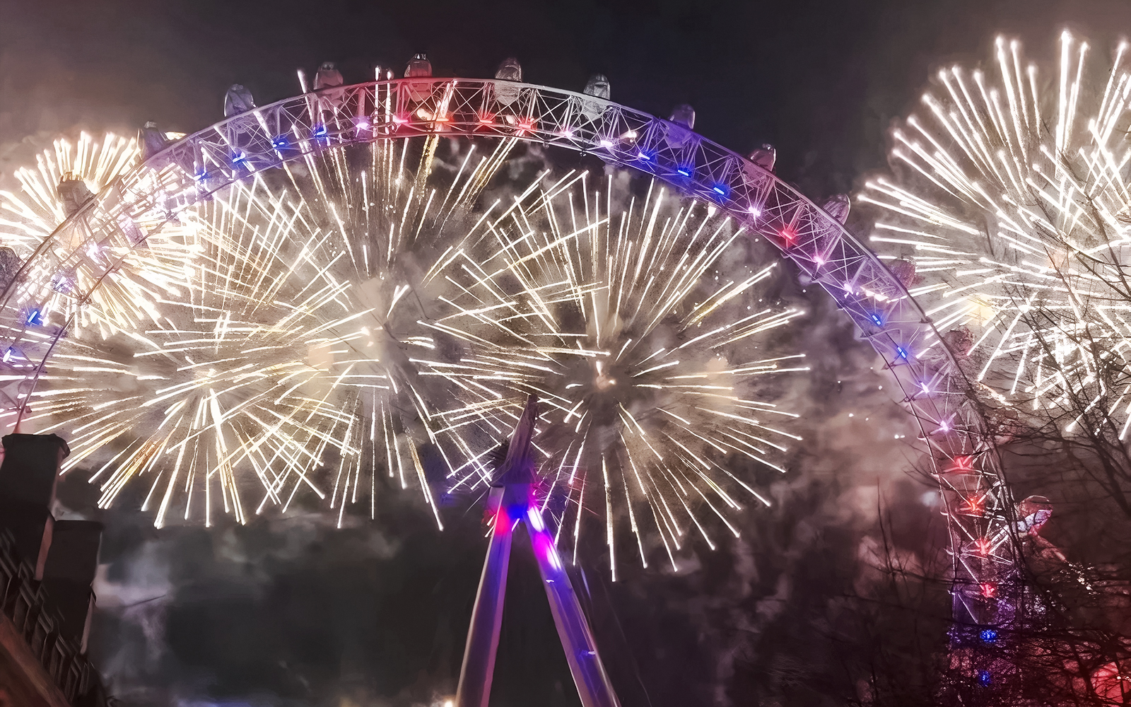 London Eye illuminated by fireworks during New Year's celebration.