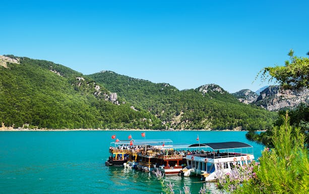 Guided boat tour on Green Canyon lake with lush hills in Antalya.