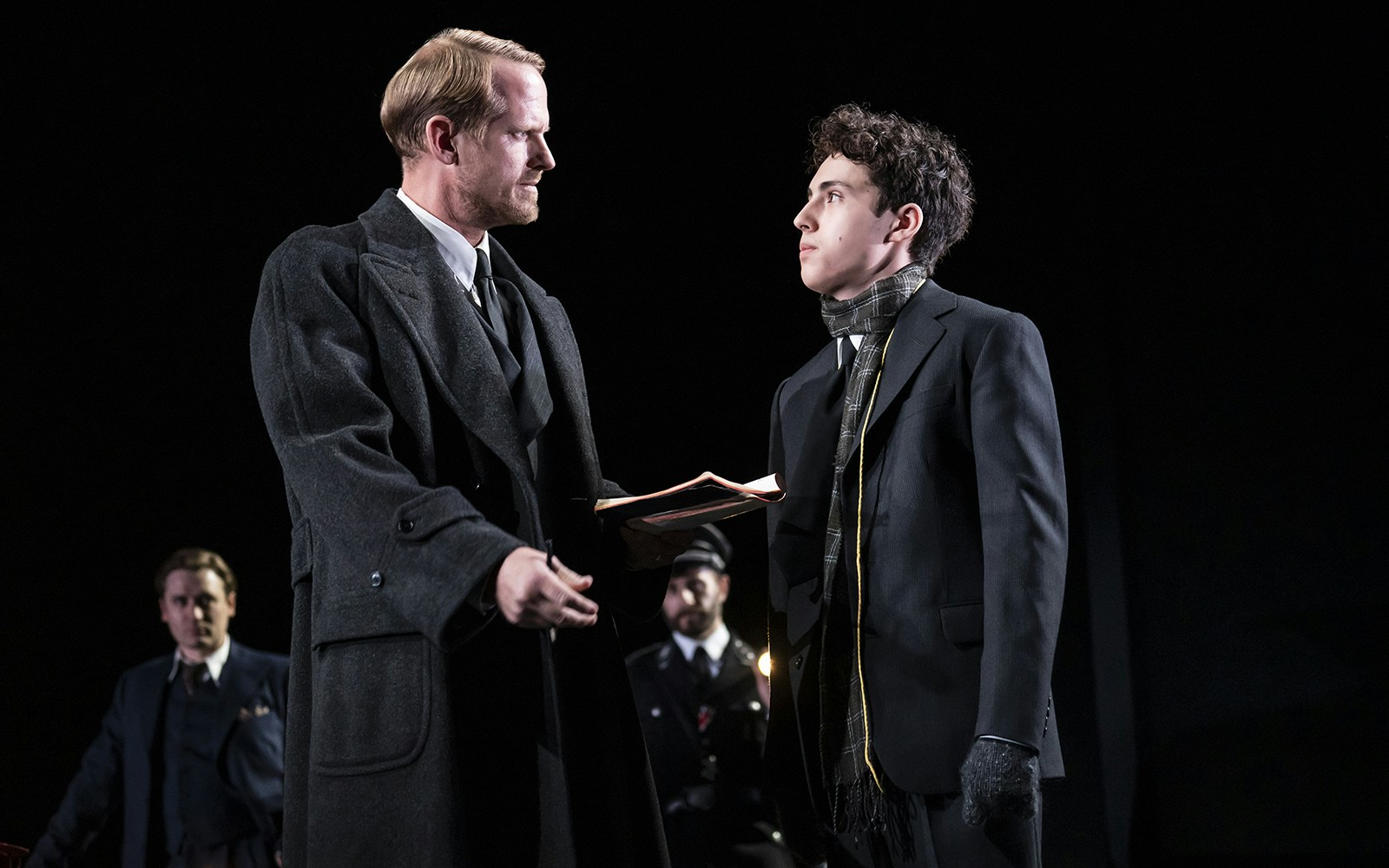 Two actors in a dramatic scene from the play Leopoldstadt, one holding a book.