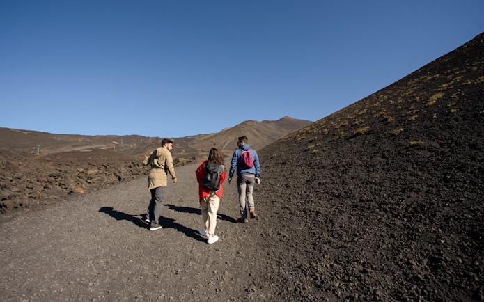 Group hiking on volcanic terrain during Half-Day Etna Jeep Tour.