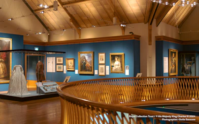 Museum gallery with historical paintings and period costumes on display.