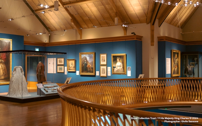 Museum gallery with historical paintings and period costumes on display.