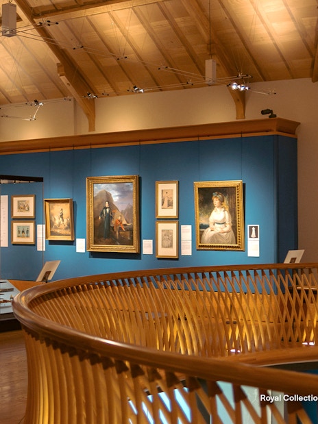 Museum gallery with historical paintings and period costumes on display.