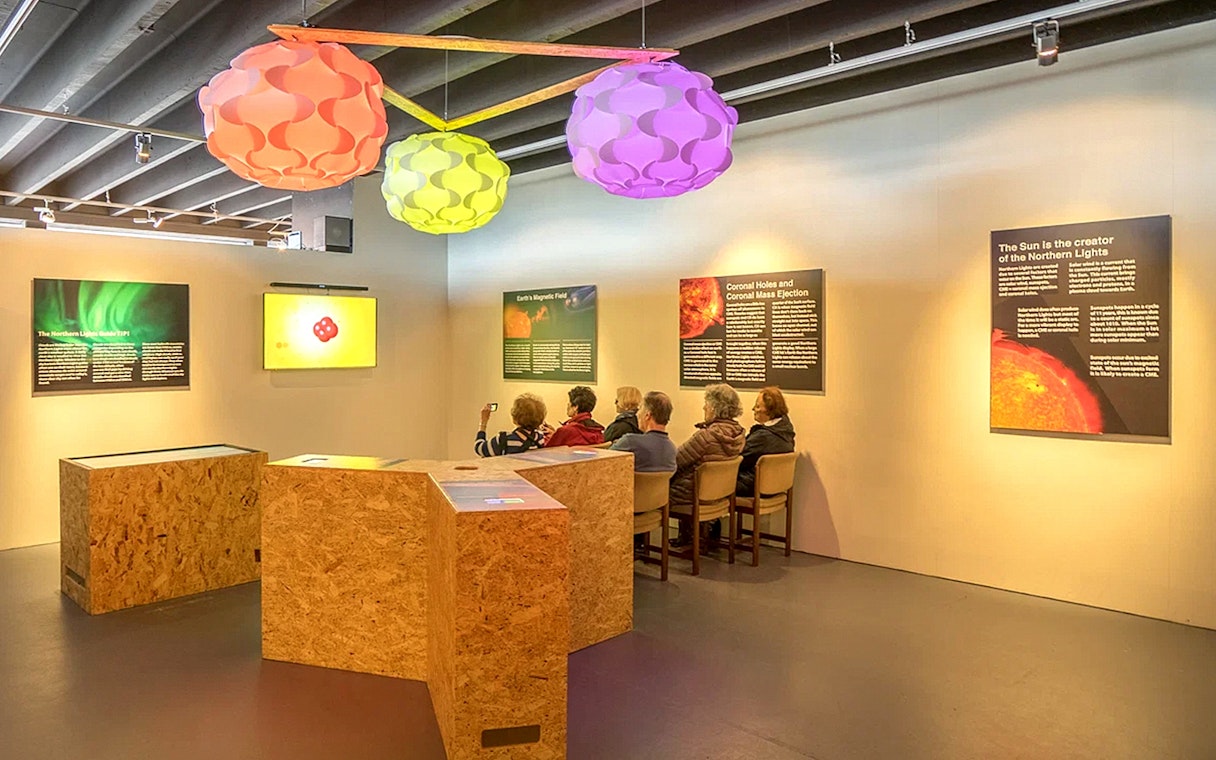 Exhibit on Northern Lights with seated visitors in Reykjavik museum.