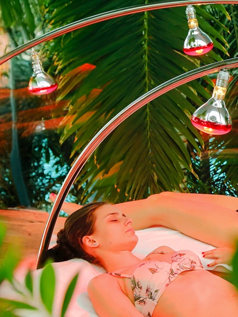 Women relaxing under infrared light beds at Therme Bucharest spa.