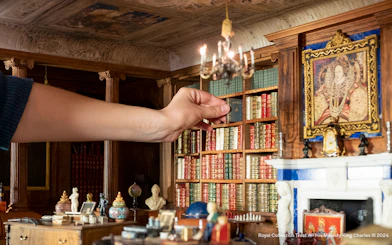 Hand arranging miniature books in Windsor Castle library model.
