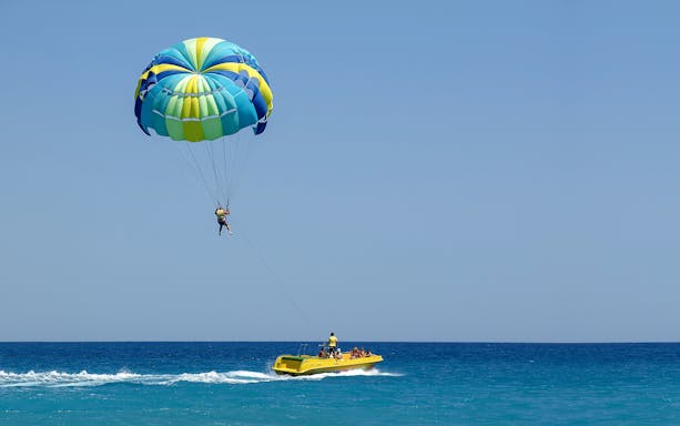 Parasailing over the ocean near Pattaya Island with a yellow speedboat below.
