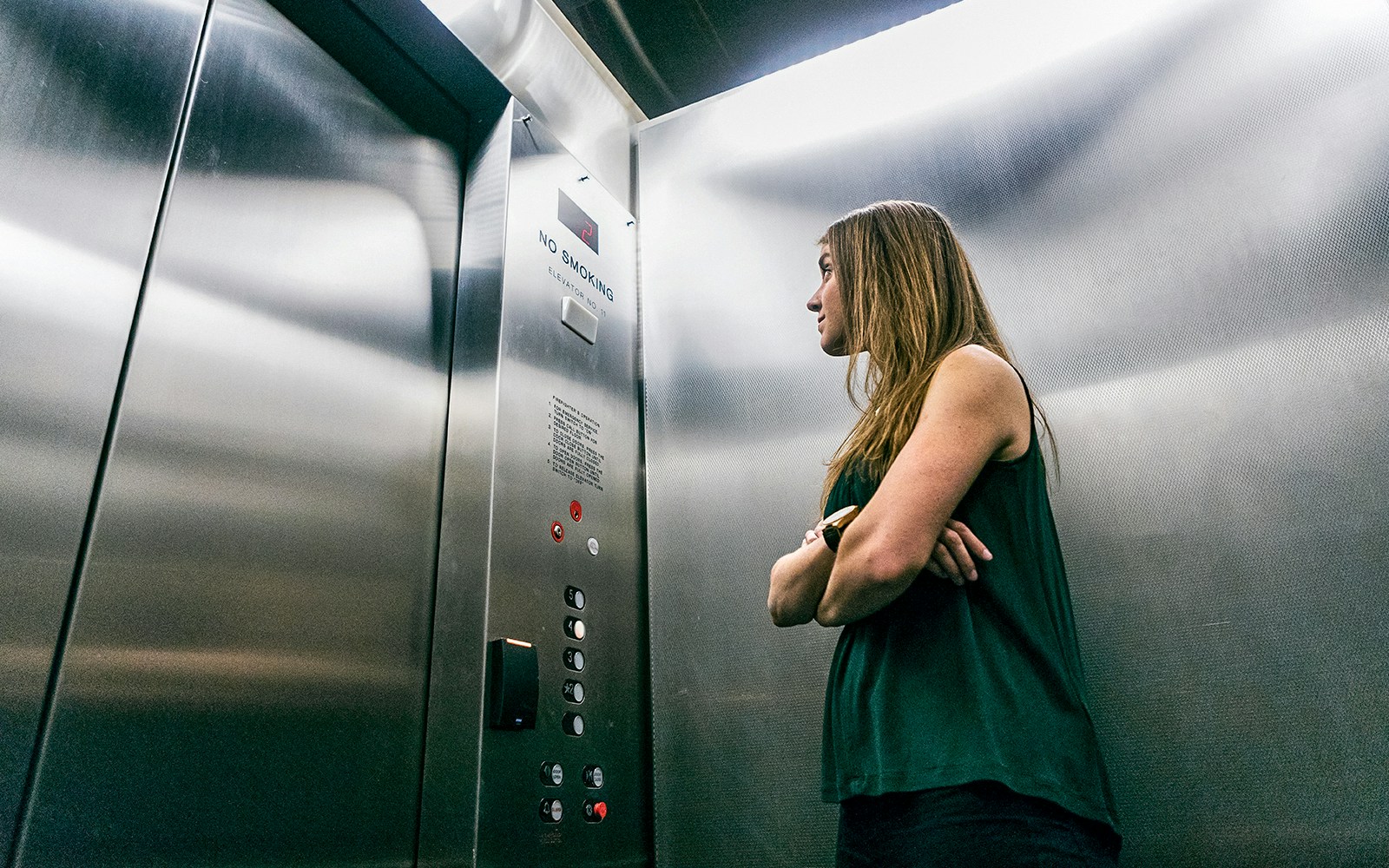 Person standing in an elevator looking at the control panel.