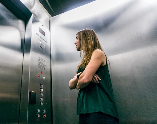 Person standing in an elevator looking at the control panel.