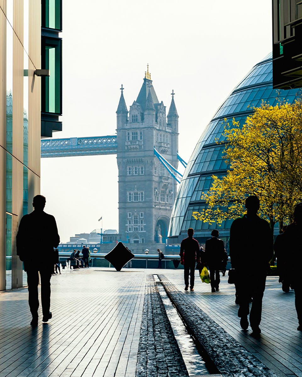 Tower Bridge view from a modern walkway in London with people walking.