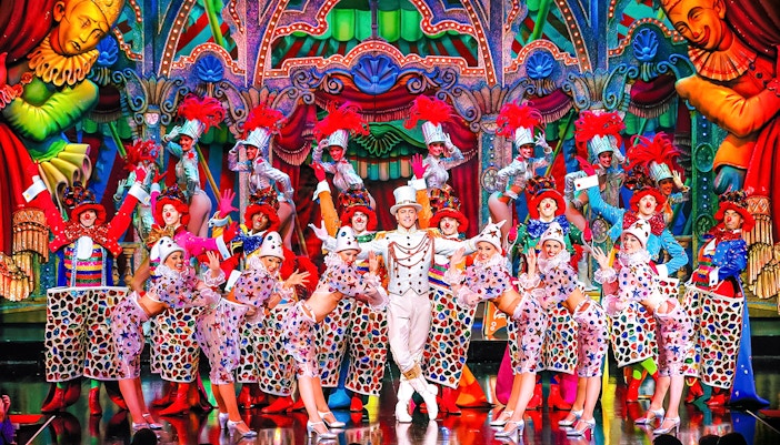 Moulin Rouge cabaret performers in vibrant costumes on stage in Paris, France.