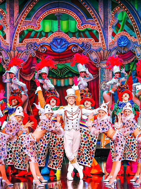 Performers in colorful costumes on stage at the Moulin Rouge show in Paris.
