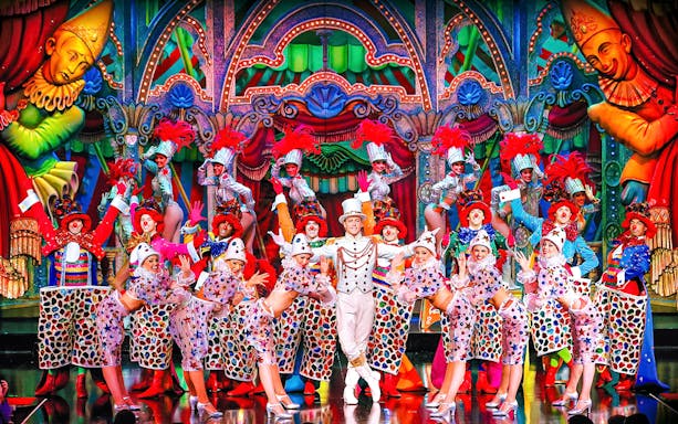 Performers in colorful costumes on stage at the Moulin Rouge show in Paris.