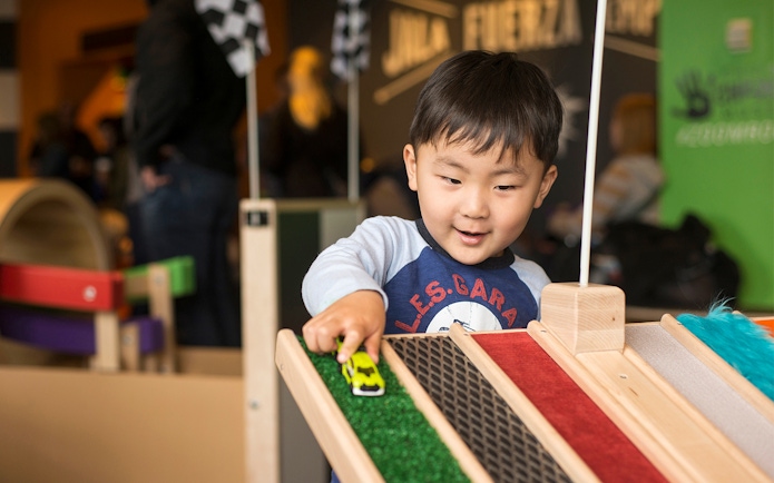 Child playing with toy car at Chicago children's museum exhibit.