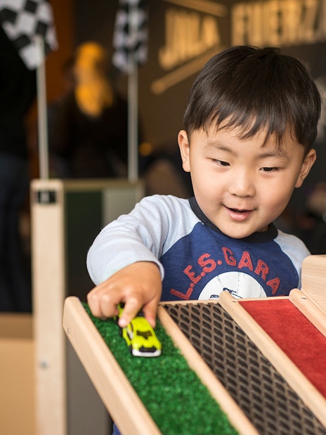 Child playing with toy car at Chicago children's museum exhibit.