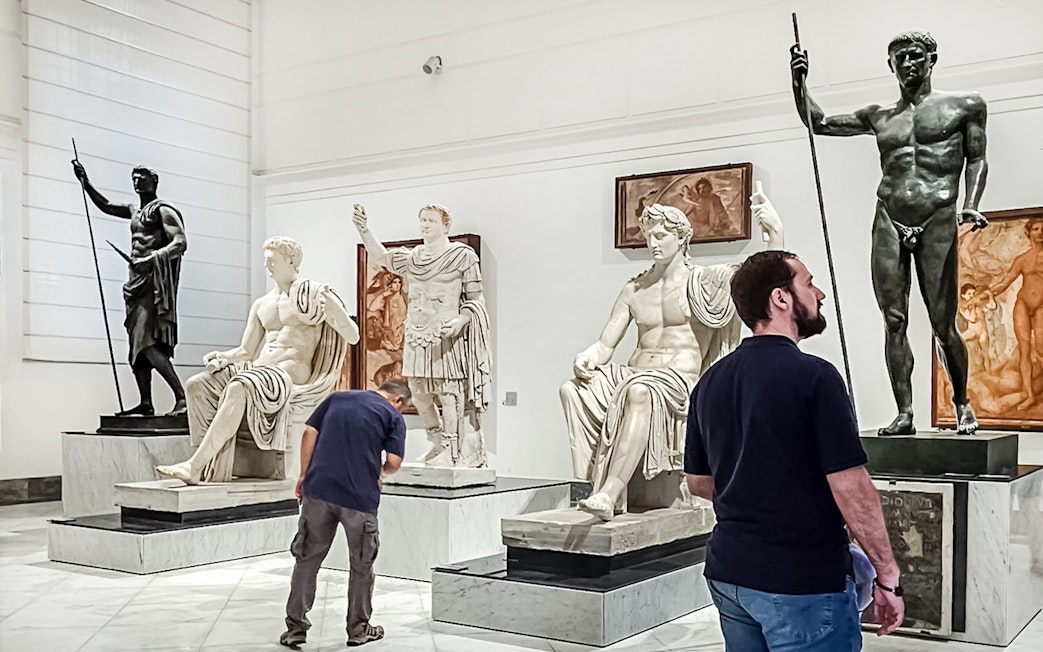 Visitors viewing classical statues at Naples National Archaeological Museum.