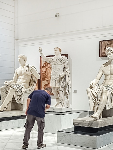 Visitors viewing classical statues at Naples National Archaeological Museum.