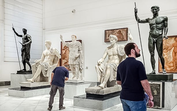 Visitors viewing classical statues at Naples National Archaeological Museum.
