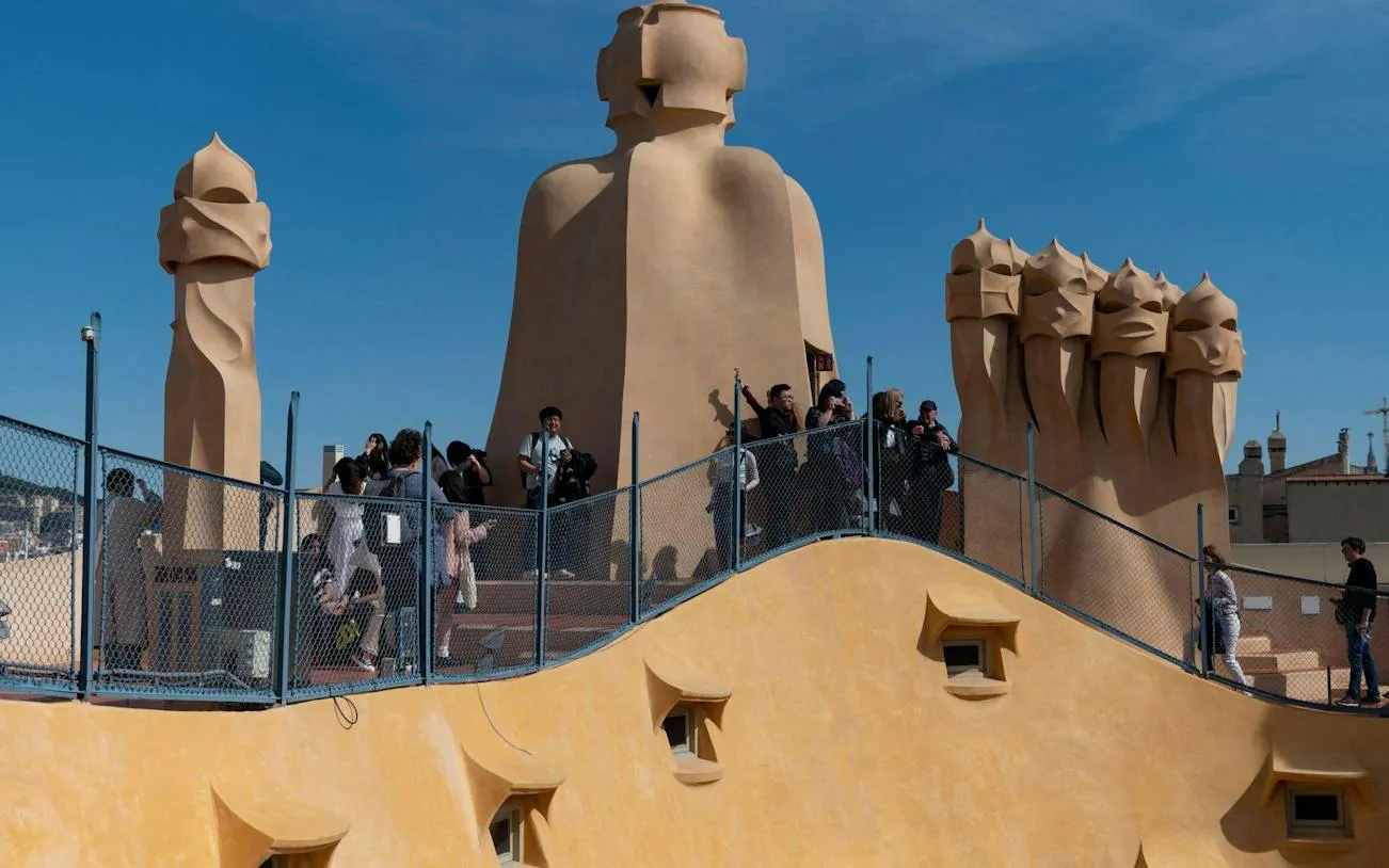 Tourists exploring rooftop chimneys of Casa Milà, Barcelona, during modernist architecture tour.