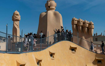 Tourists exploring rooftop chimneys of Casa Milà, Barcelona, during modernist architecture tour.