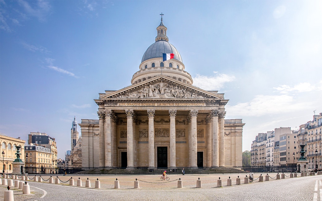 Pantheon in Paris with French flag on dome, viewed from the front.
