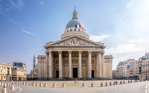Pantheon in Paris with French flag on dome, viewed from the front.