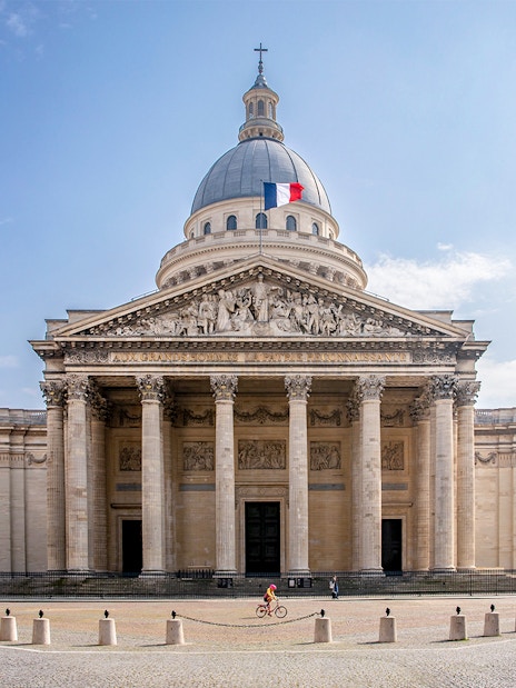 Pantheon in Paris with French flag on dome, viewed from the front.