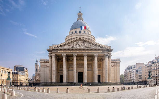 Pantheon in Paris with French flag on dome, viewed from the front.
