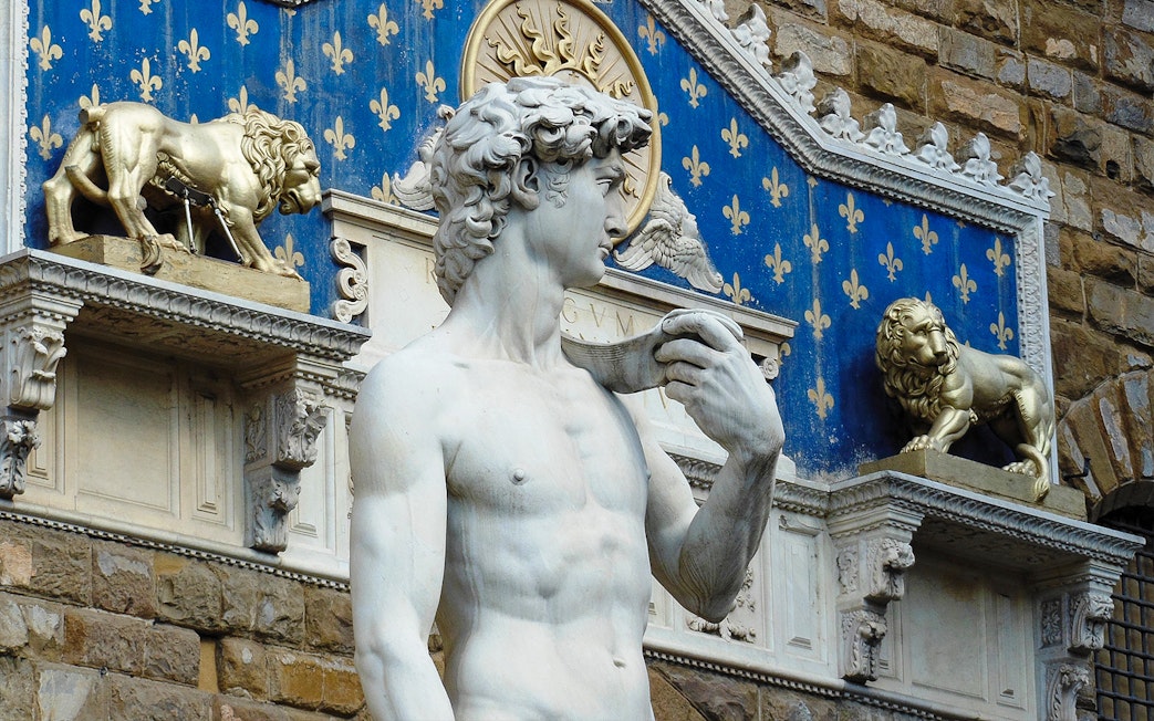 Statue of David at Palazzo Vecchio, Florence, with decorative lions in the background.