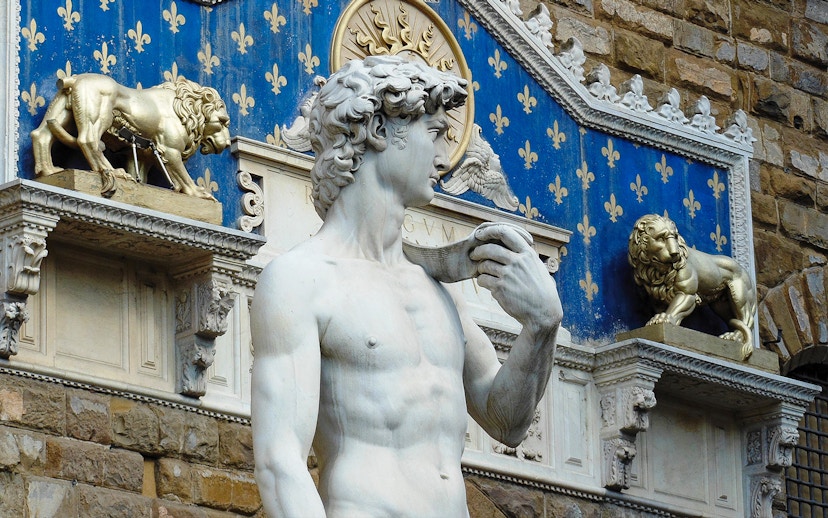 Statue of David at Palazzo Vecchio, Florence, with decorative lions in the background.