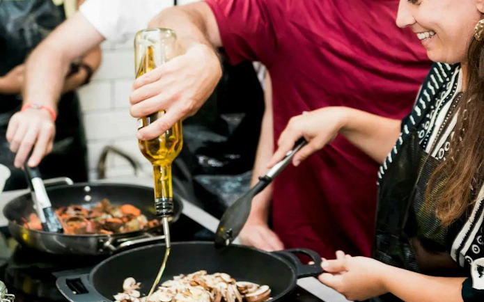 Cooking class participants preparing paella with olive oil in Barcelona.