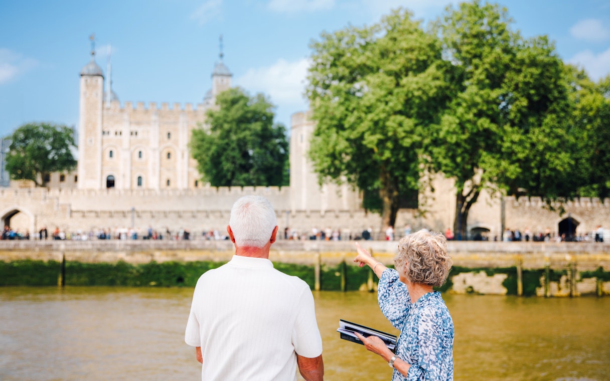 Guests viewing the Tower of London from a cruise boat on the River Thames.