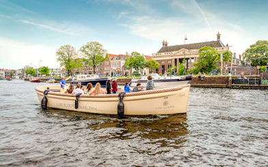 Open boat tour on Haarlem canal with passengers enjoying city views.