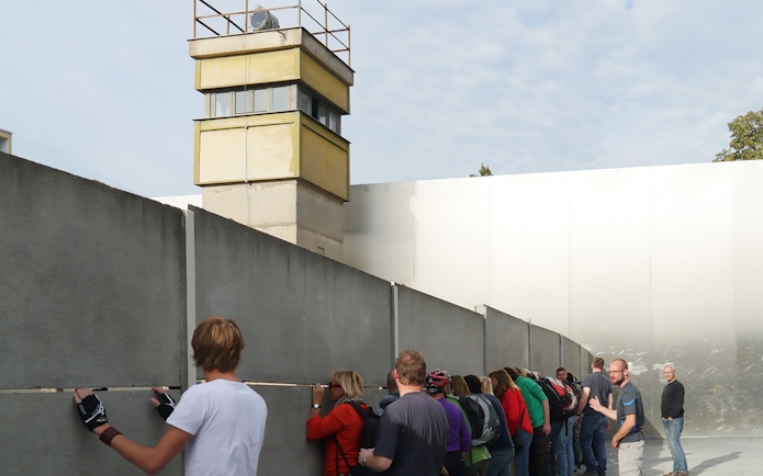 Visitors examining Berlin Wall remains on a guided bike tour.