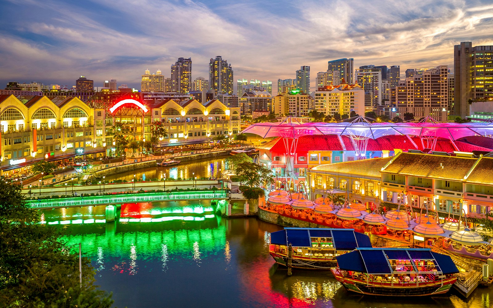 Singapore River Cruise with vibrant Clarke Quay lights and city skyline at dusk.