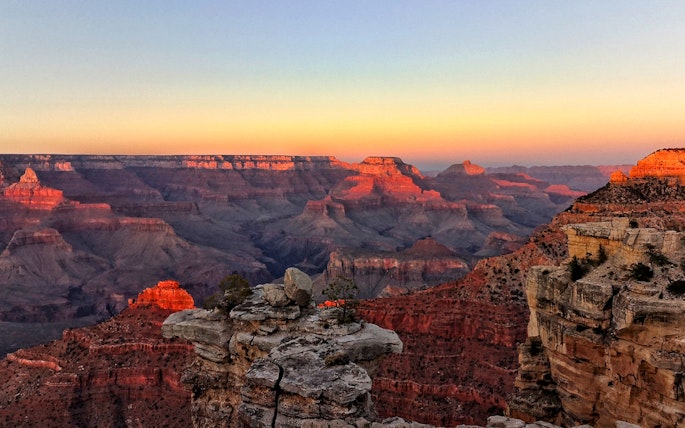 Grand Canyon at sunset with layered rock formations and vibrant colors.
