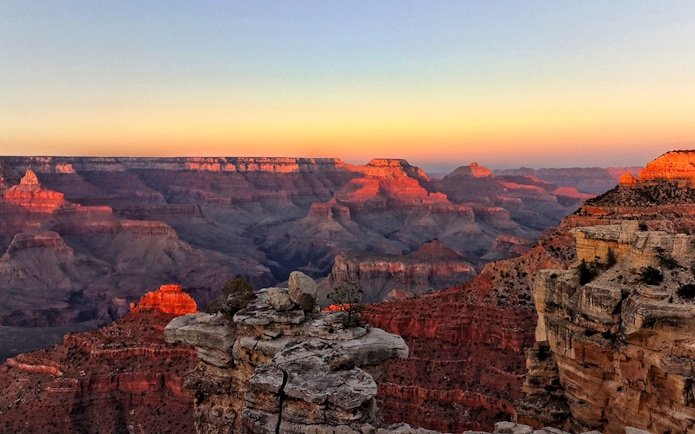 Grand Canyon at sunset with layered rock formations and vibrant colors.