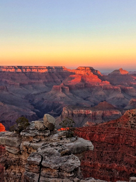 Grand Canyon at sunset with layered rock formations and vibrant colors.